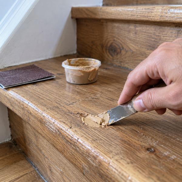 Application de mastic à bois sur une petite marque d'une marche en bois